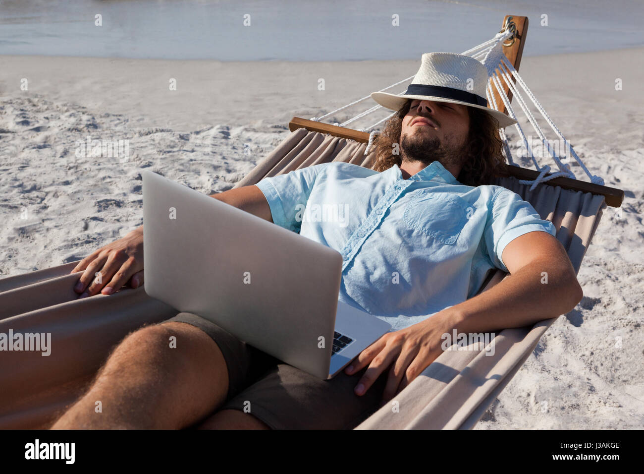 Man with laptop relaxing on hammock at beach Stock Photo Alamy
