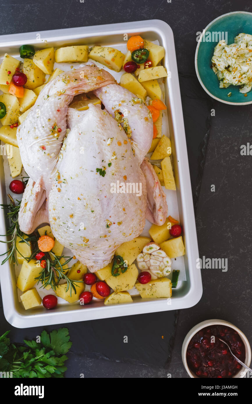 Whole raw chicken seasoned with butter and herbs for roasting Top view