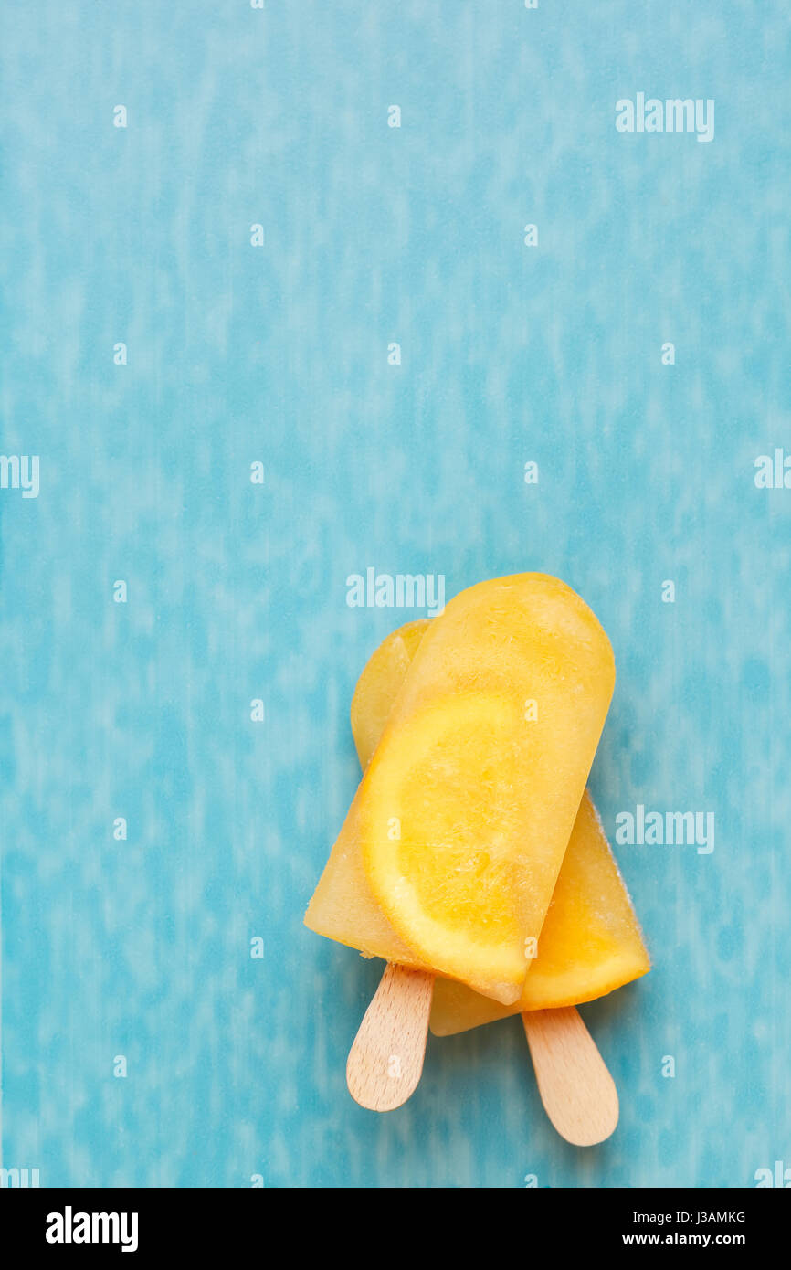 Fruit ice cream lollies on a blue surface. Top view, copy space Stock