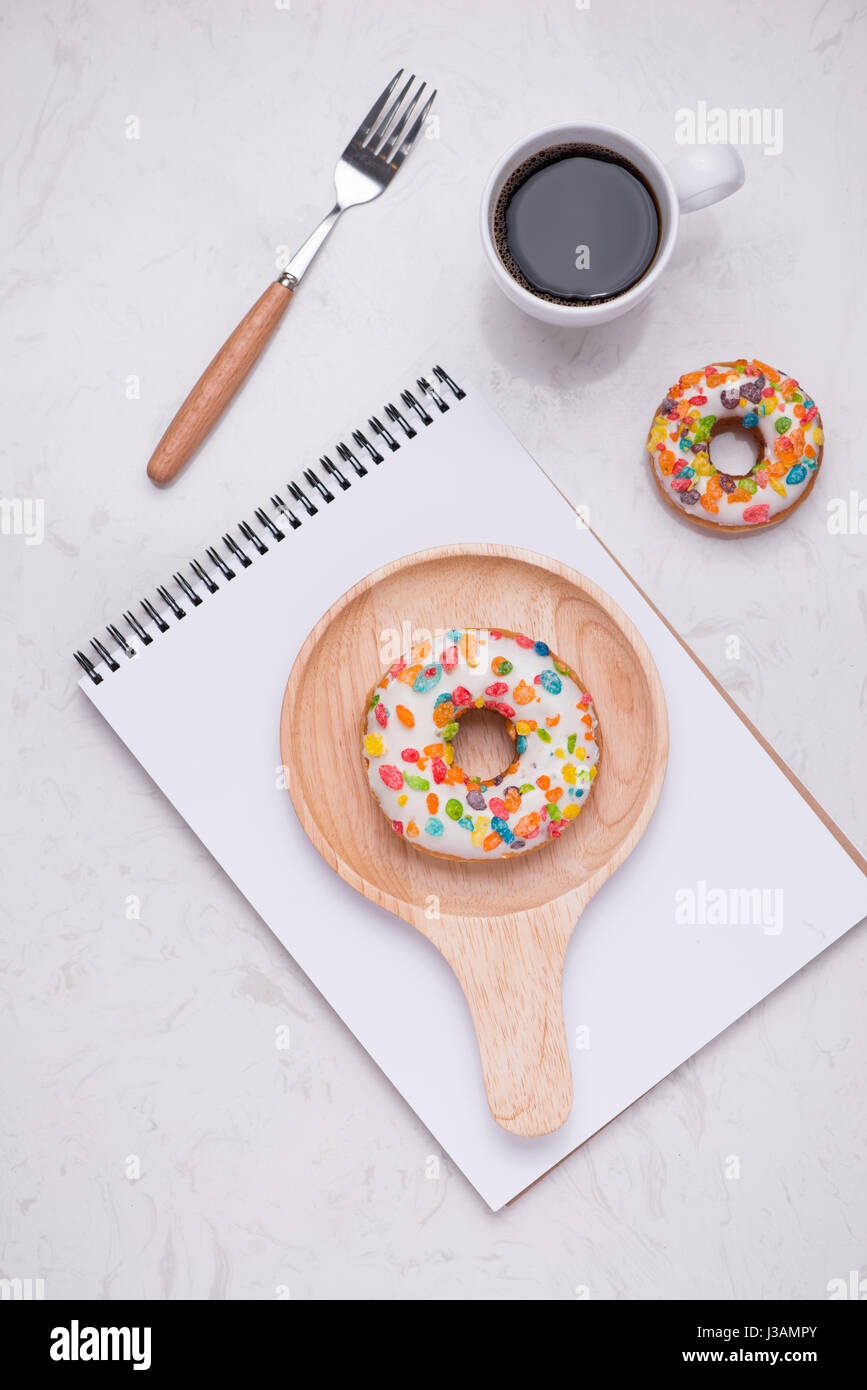 Working desk with dessert and coffee. Cake donuts with a cup of espresso on marble table top. Stock Photo