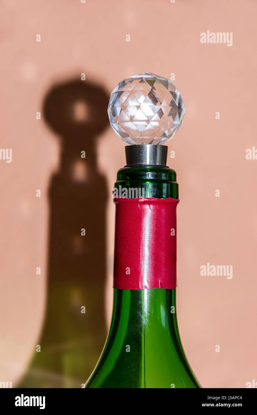 Wine bottle with cap throws shadow on the wall. Stock Photo