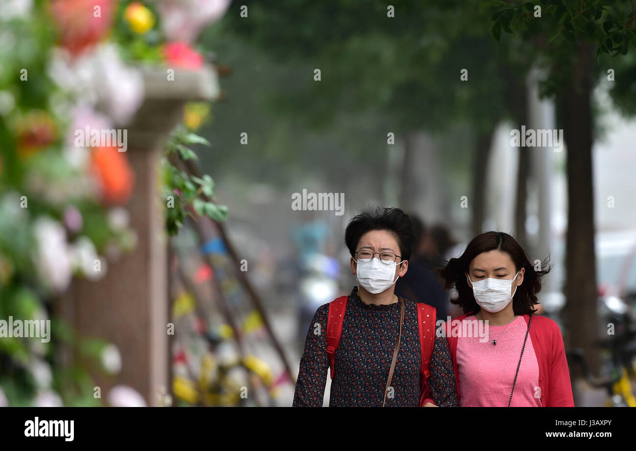 Tianjin, China. 4th May, 2017. People wearing masks walk in Tianjin ...