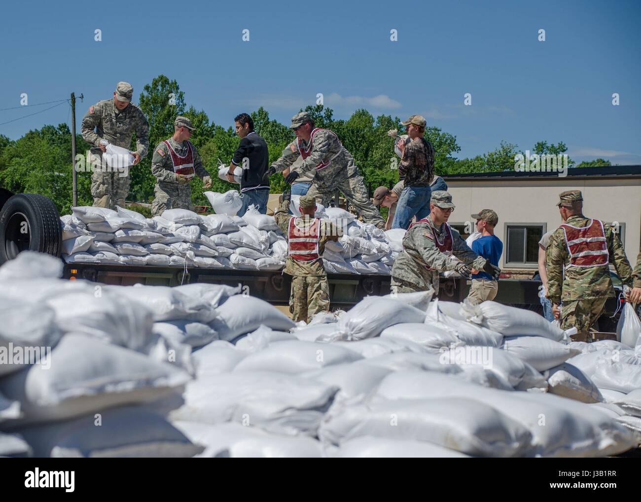 Missouri National Guardsmen and student volunteers work to build a support wall with sandbags to support a levee against floodwaters May 2, 2017 in Poplar Bluff, Missouri. Historic flooding has swamped towns across Arkansas and Missouri with at least 20 people reported dead. Stock Photo