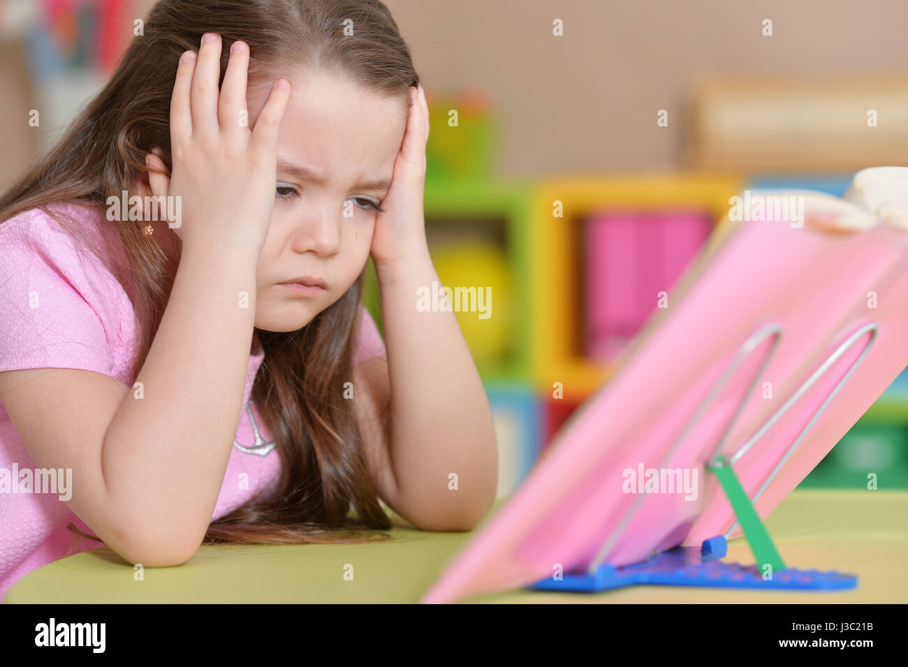 Girl is sitting at the table and reading a book Stock Photo - Alamy