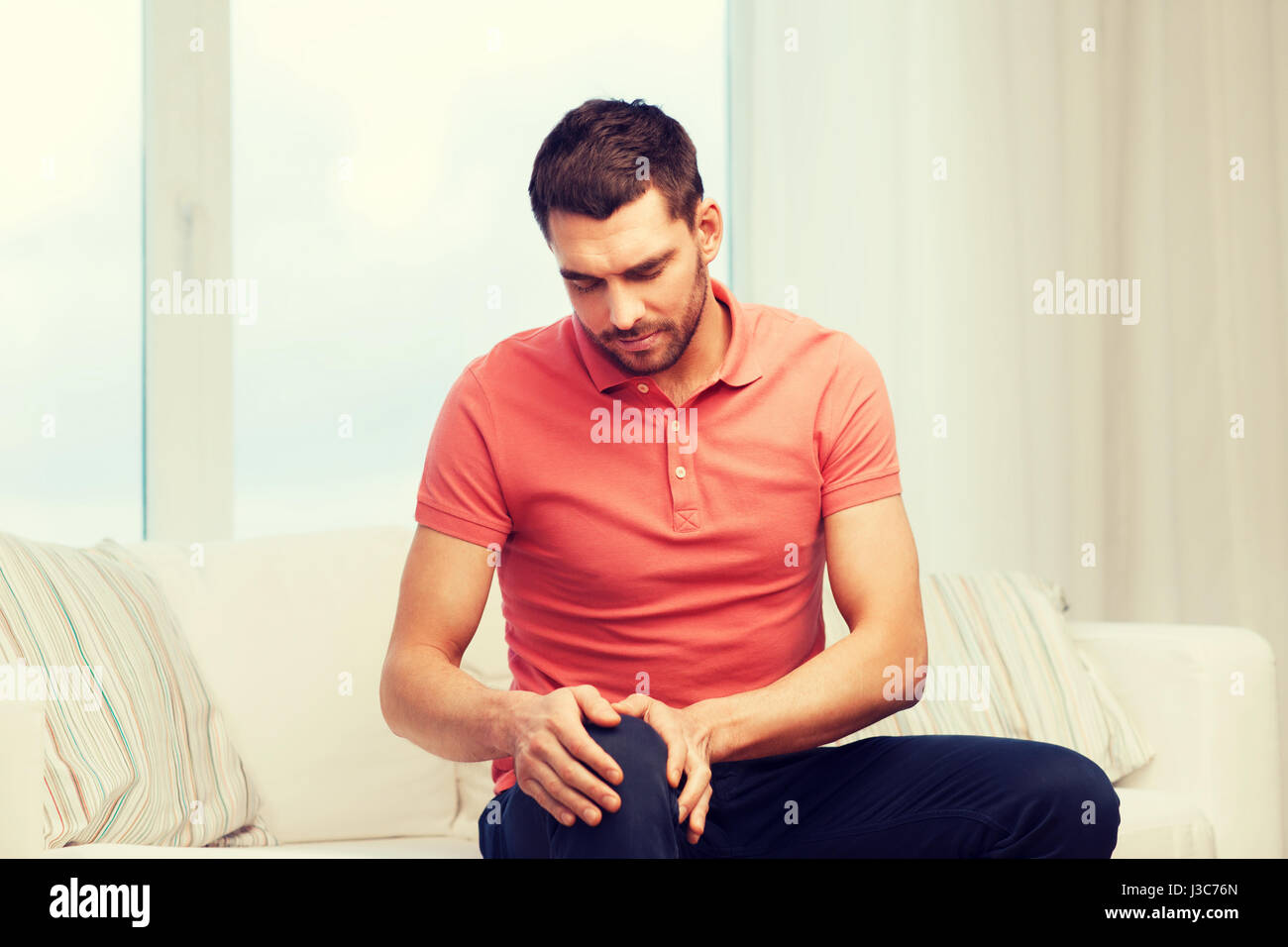 unhappy man suffering from pain in leg at home Stock Photo - Alamy