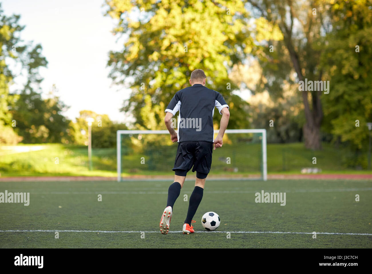 soccer player playing with ball on football field Stock Photo