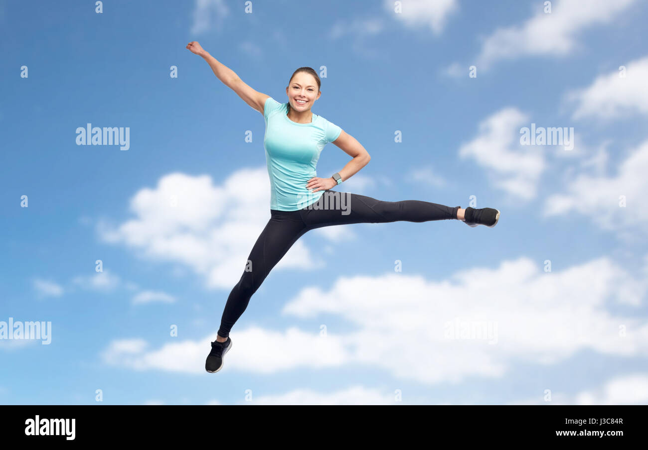 happy sporty young woman jumping in blue sky Stock Photo - Alamy
