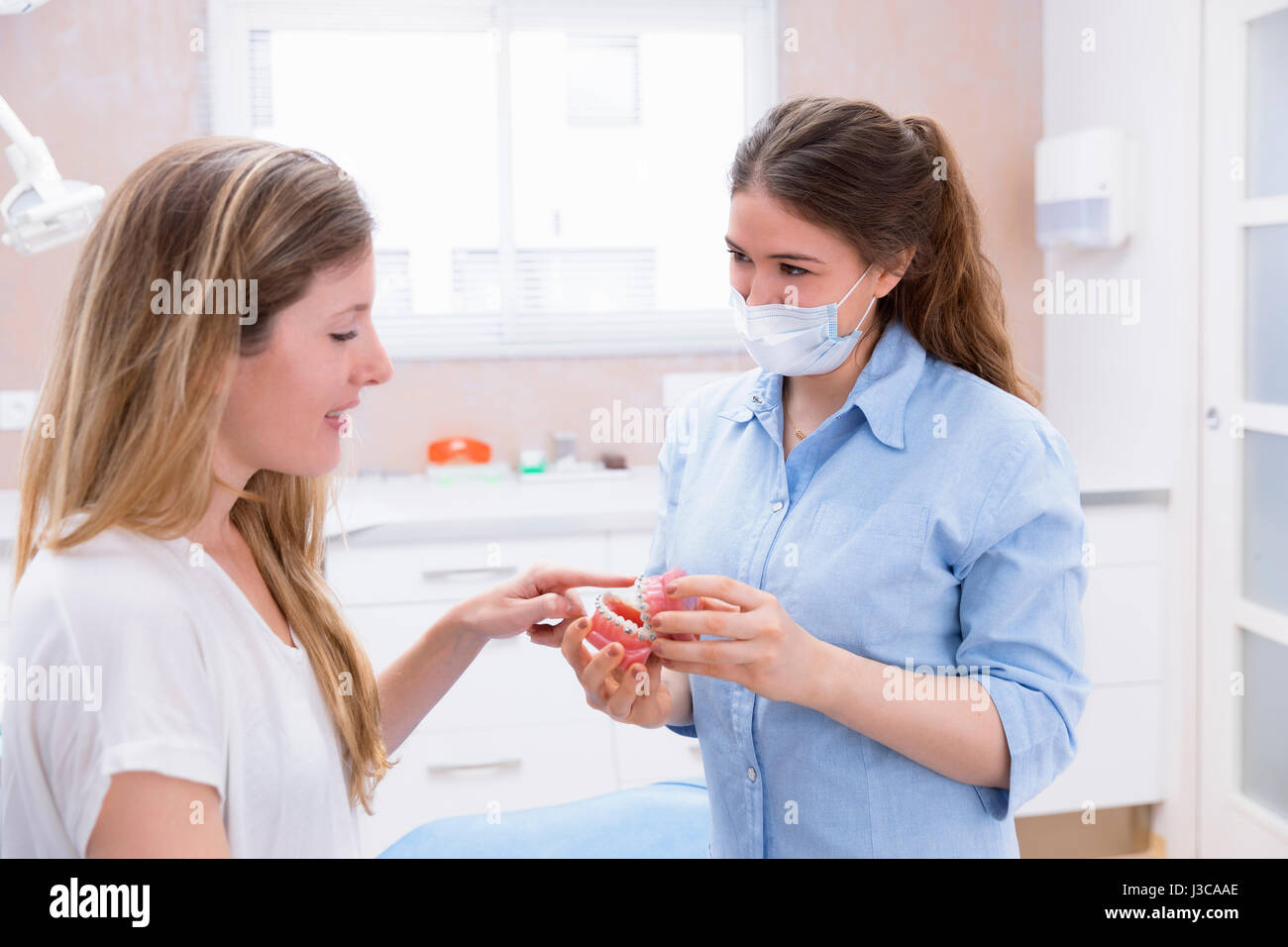 orthodontist woman shows tool teeth model with metal wired dental ...
