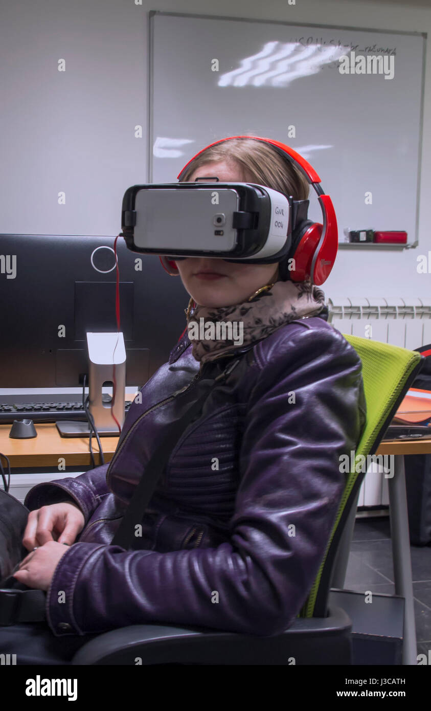 A girl sitting and wearing gear for 360 degrees video experience. Stock Photo