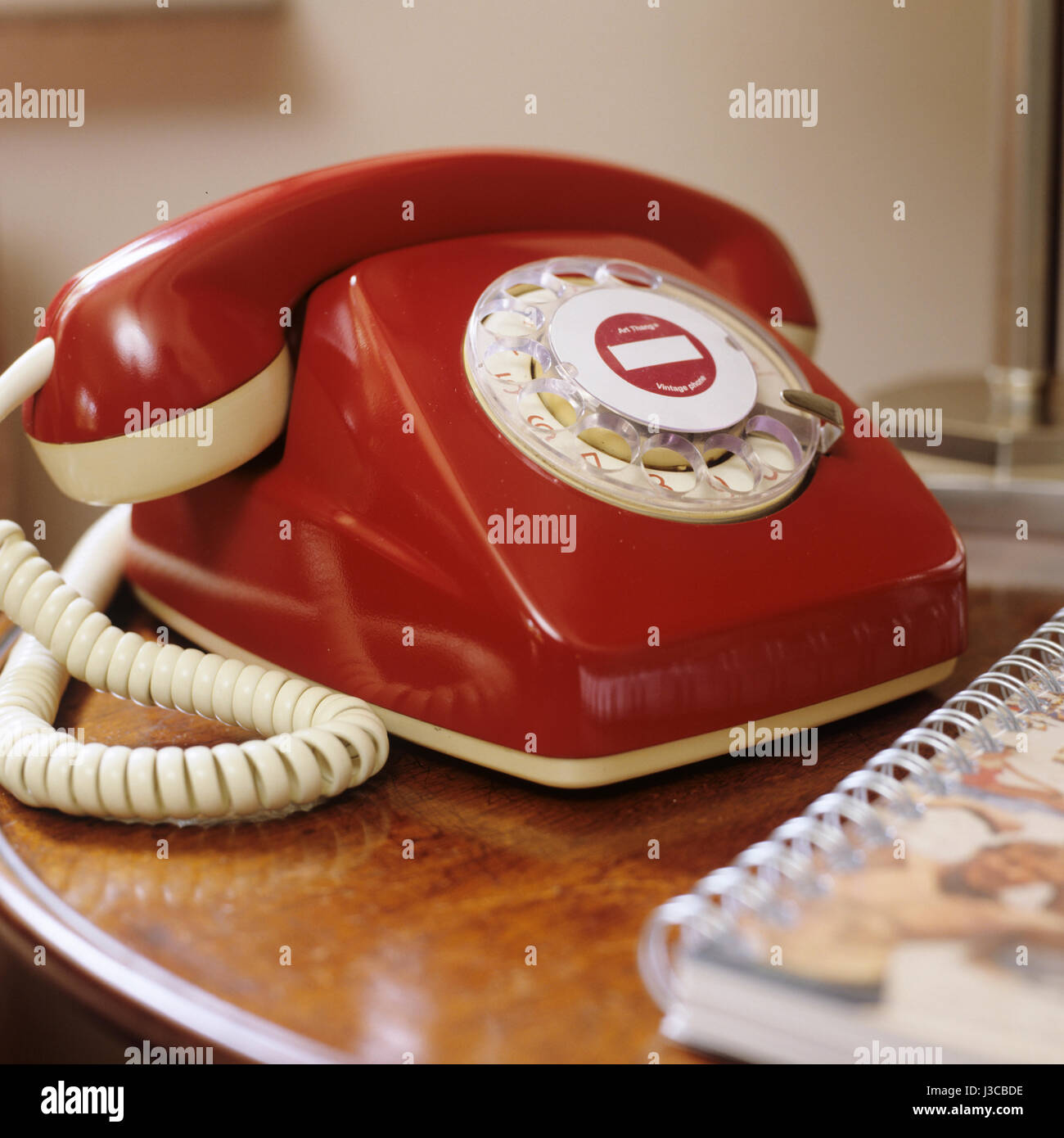 A red Art Thang vintage phone on side table with note book Stock Photo