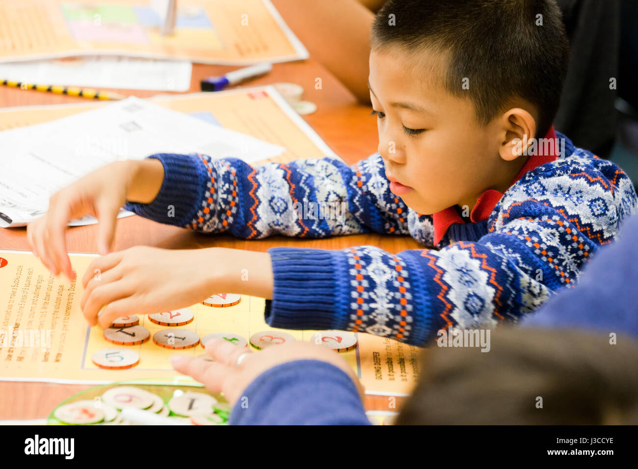 Asian child learning math at interactive stations at math fair - USA Stock Photo