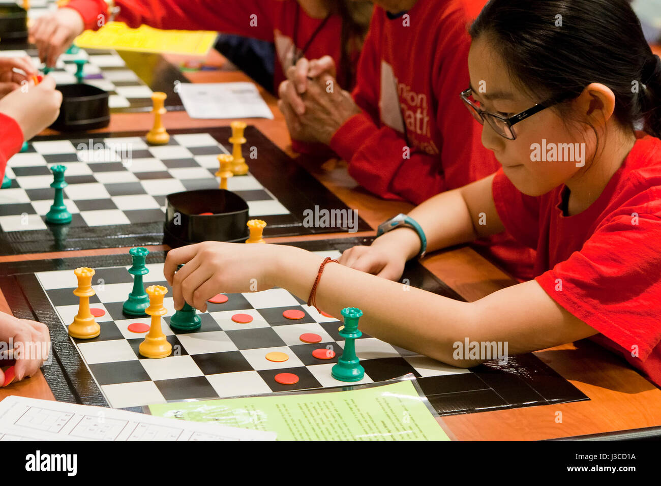 Female Asian teen playing Game of the Amazons board game - USA Stock Photo