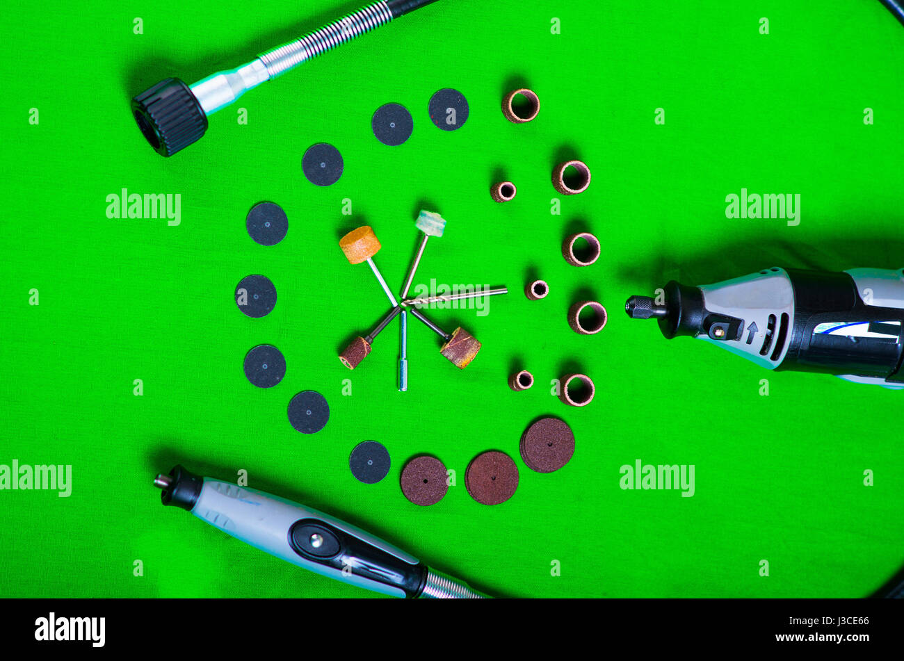 A gray drill with drilling accessories on green background aerial view
