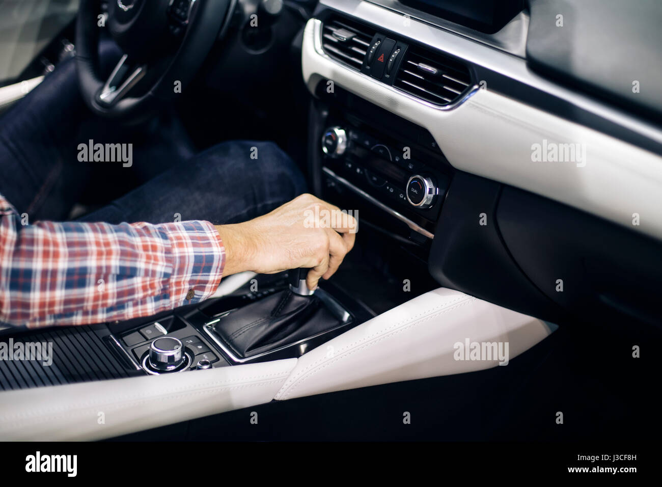 View at young handsome man changing gears during driving of modern car