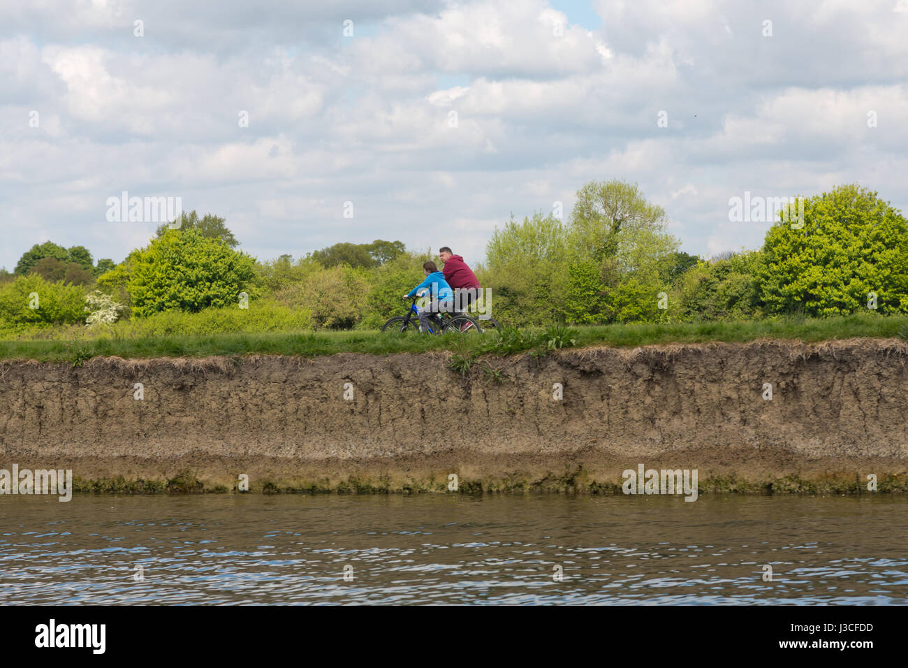 A man and son cycling on the river thames bank Stock Photo