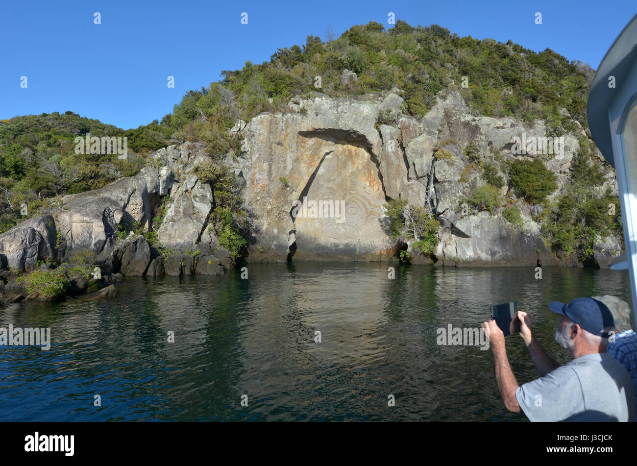 TAUPO, NZL - APR 26 2017:Visitors photographing the iconic Maori Rock Carving at lake Taupo in the North Island of New Zealand. Stock Photo