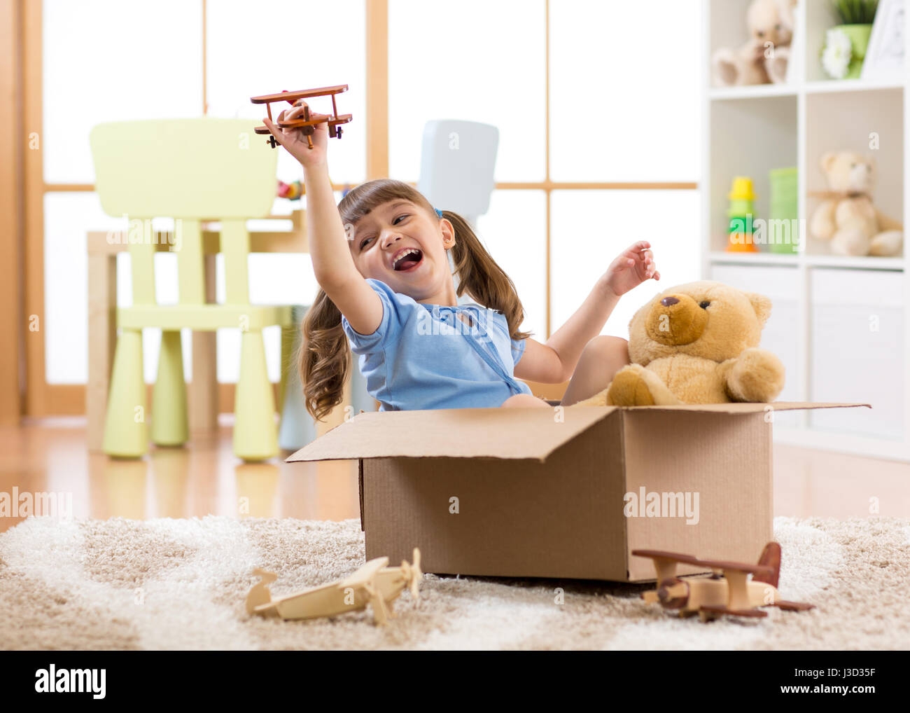 Kid playing pilot flying a cardboard box in children room Stock Photo