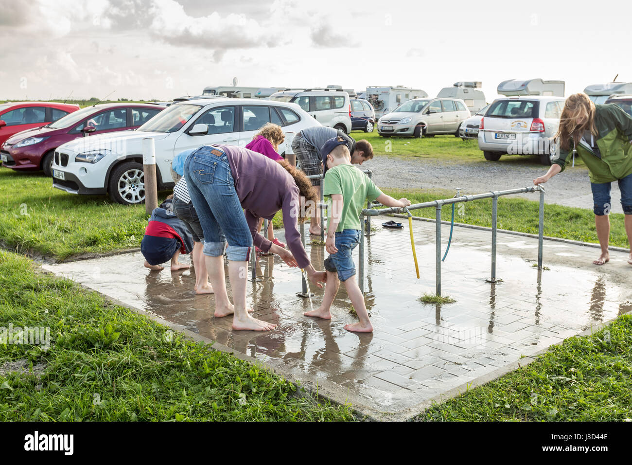 people cleaning their feet near the mud flat of Nessmersiel - Nessmersiel, Lower Saxony, Niedersachsen, Germany, Europe, EU Stock Photo