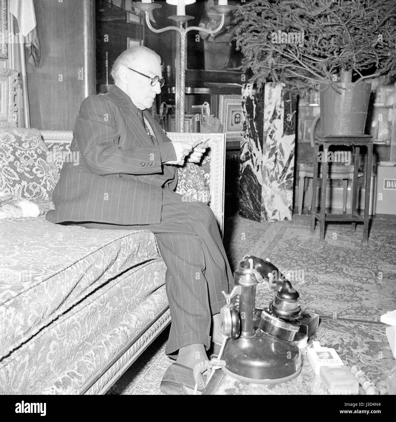 French actor, playwright and director Sacha Guitry in the living room of his Paris apartment located 18 avenue Elisée Reclus. c.1955 Photo Georges Rétif de la Bretonne Stock Photo