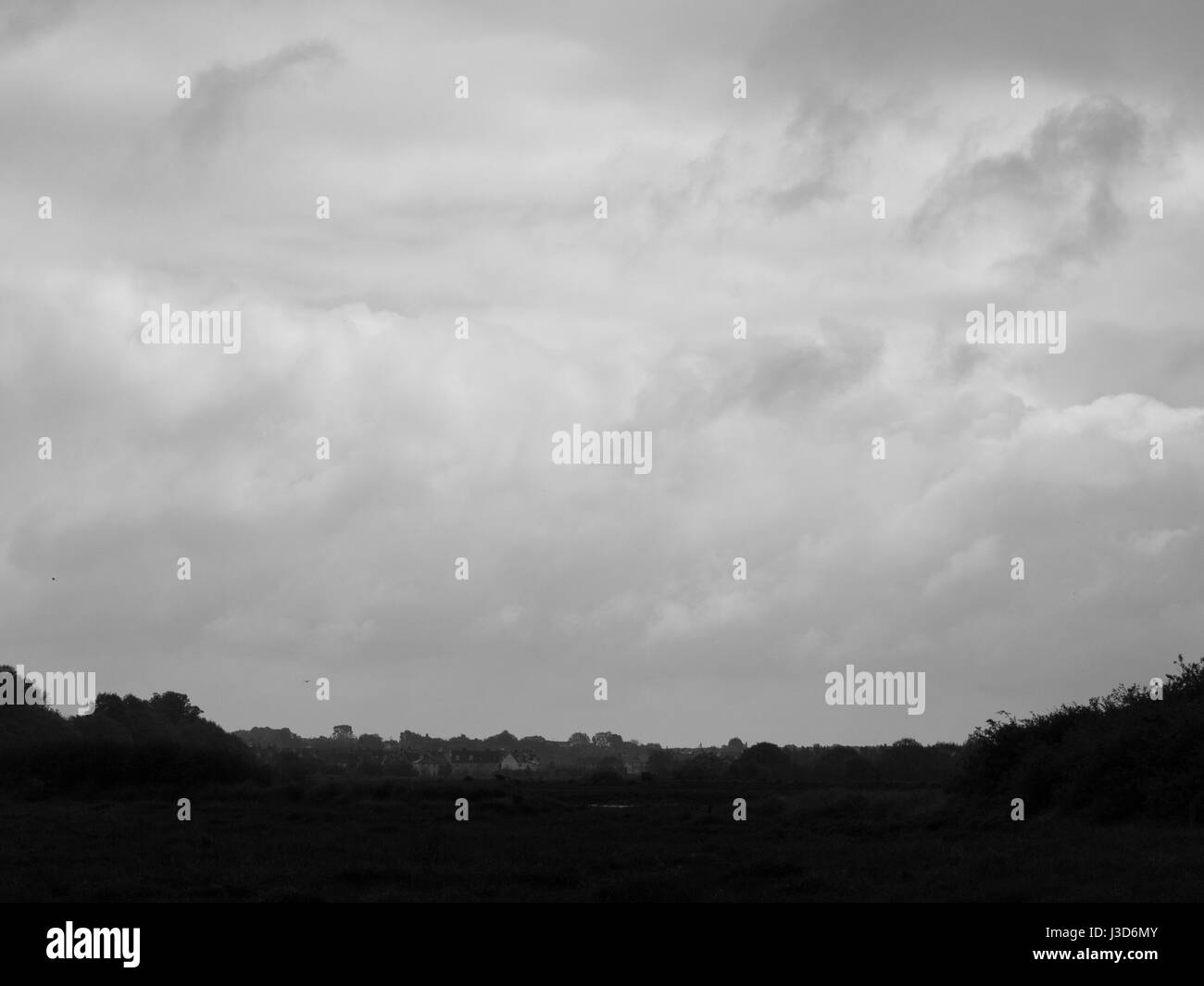 black and white overcast clouds over small town and field dark Stock Photo