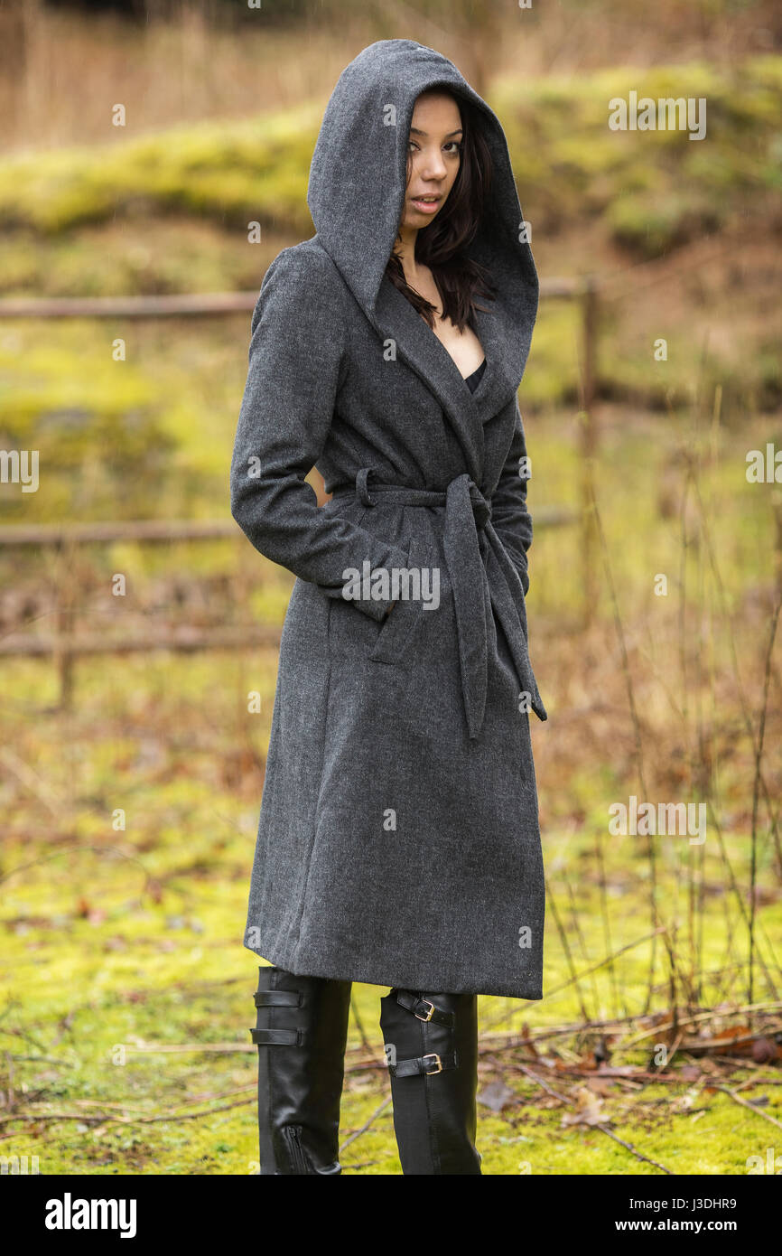 A young woman walking in the countryside dressed in a hooded coat Stock Photo