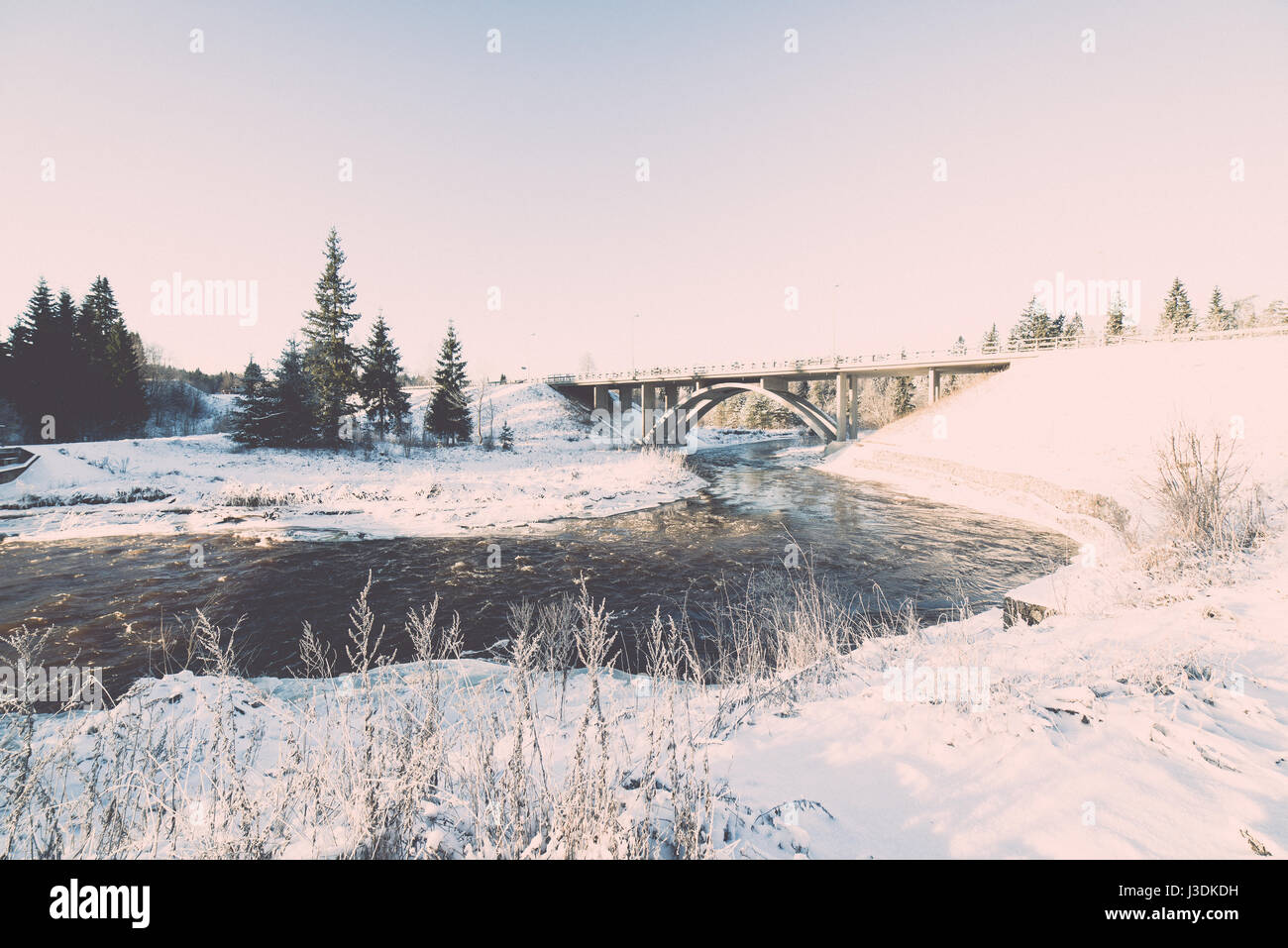 snowy winter river landscape with metal bridge and blue sky - retro ...