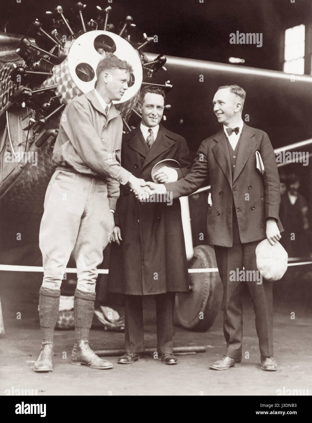 Rival aviators Charles Lindbergh and Clarence Chamberlin shaking hands in front of Lindbergh's Spirit of St. Louis airplane, with famed explorer and pilot Richard Byrd standing between them, in May, 1927 prior to competing attempts to complete the first transatlantic flight. Stock Photo