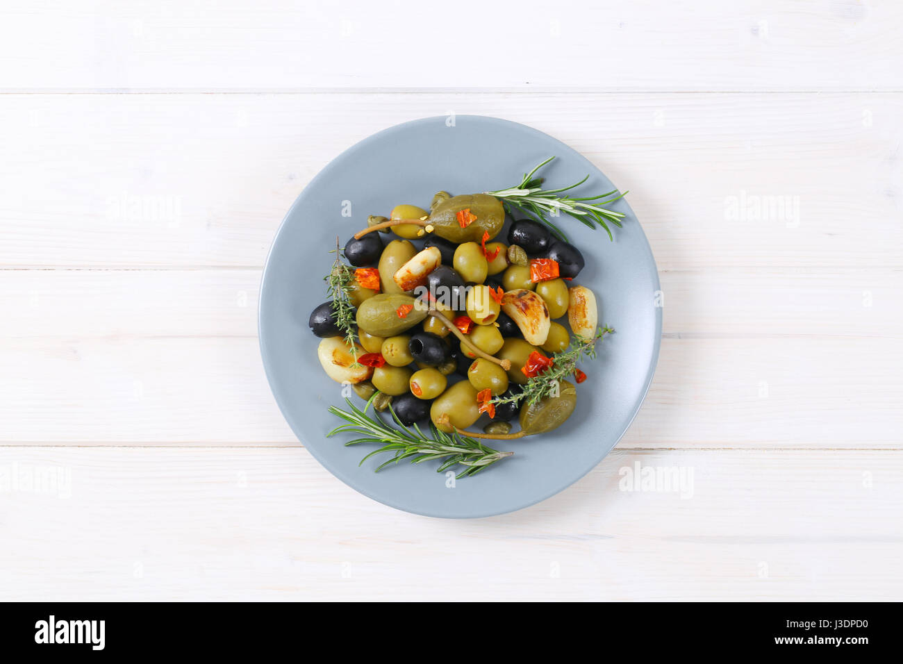 Plate of green and black olives with garlic, capers and caper berries Stock Photo