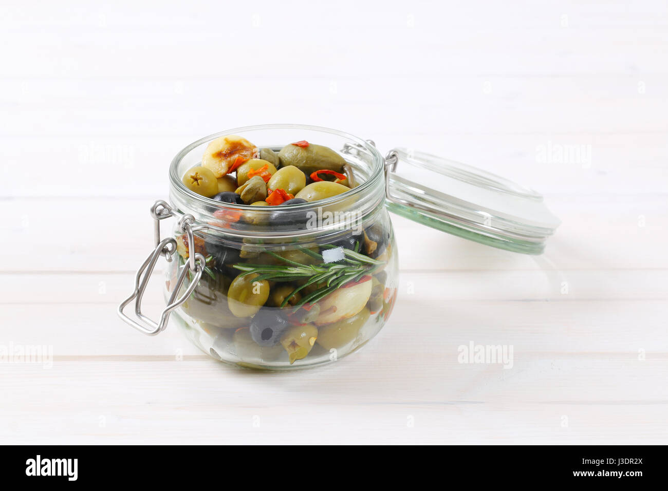 jar of pickled olives, capers, caper berries and garlic Stock Photo