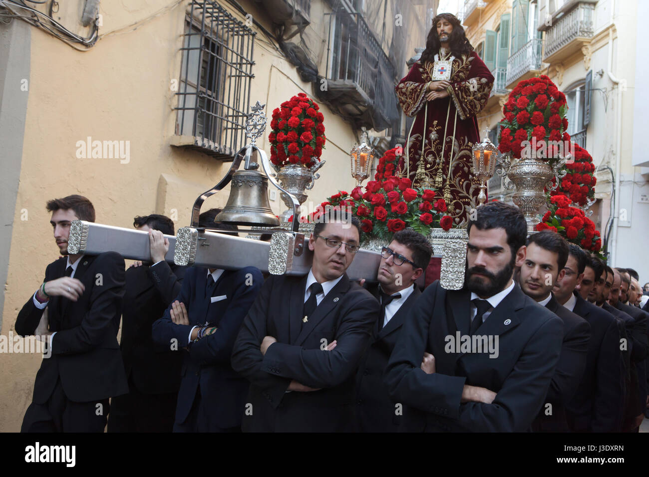 Catholic faithful carry the statue of El Cristo de Medinaceli (Christ of Medinaceli) in the ceremonial street procession from Saint James' Church (Iglesia de Santiago Apostol) to the Church of Santo Cristo de la Salud in Malaga, Andalusia, Spain, on January 7, 2016, due the finishing of the restoration works in the church. Stock Photo