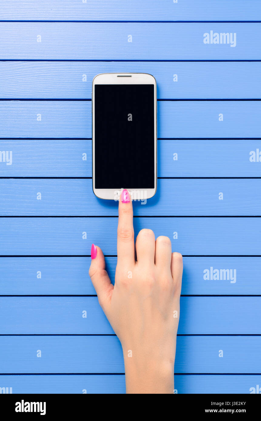 Beautiful female hand using mobile phone over blue wooden table Stock ...