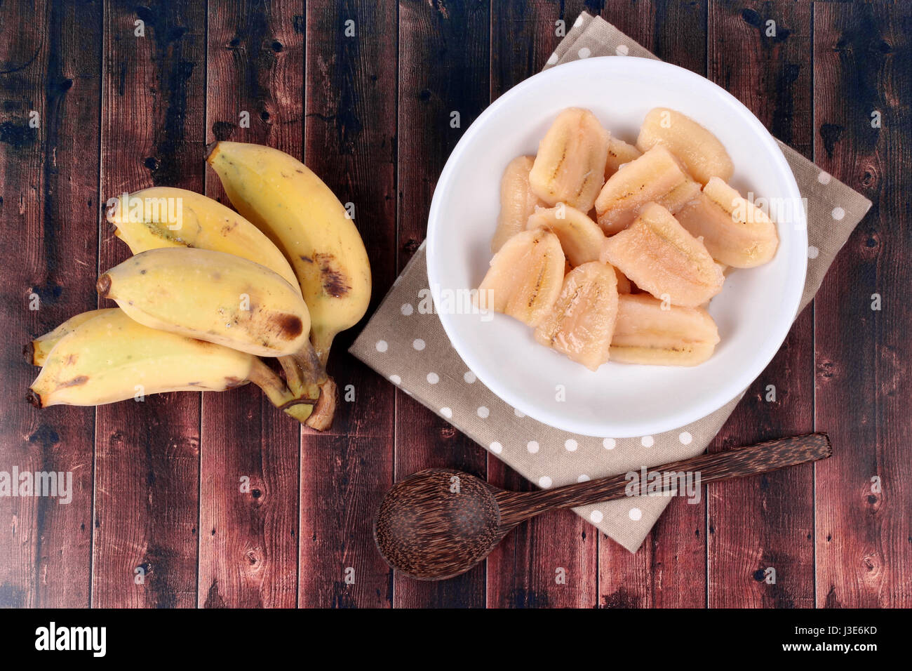 Thai popular dessert , Ready served of boiled banana in syrup and wholes of banana served on wood. Stock Photo