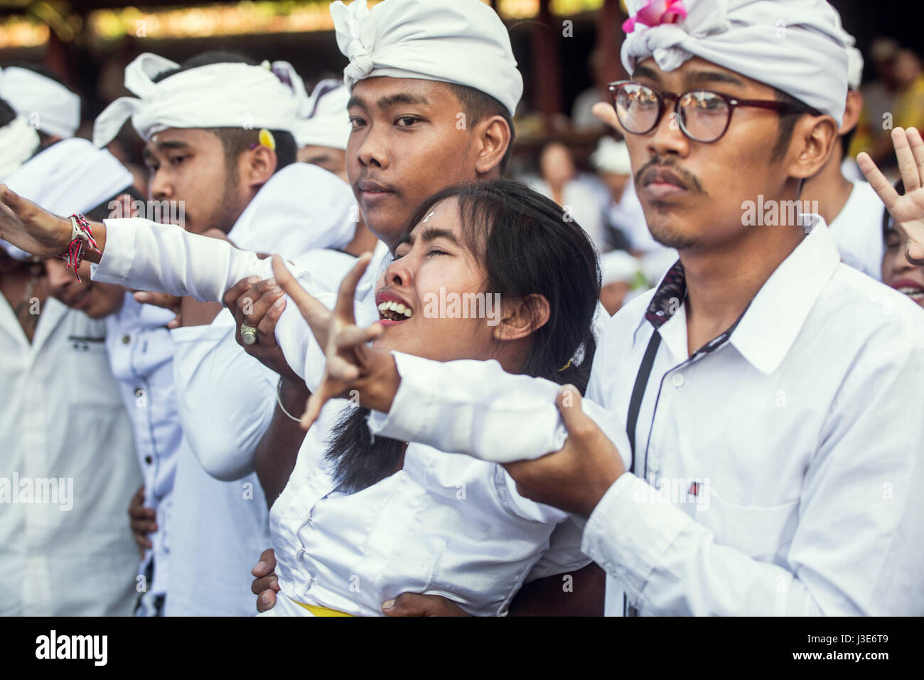 Religious woman in trance appears to be suffering at a Bali ceremony aided by devotees during the Sakral Ritual at the Hindu Pengerebongan ceremony Stock Photo