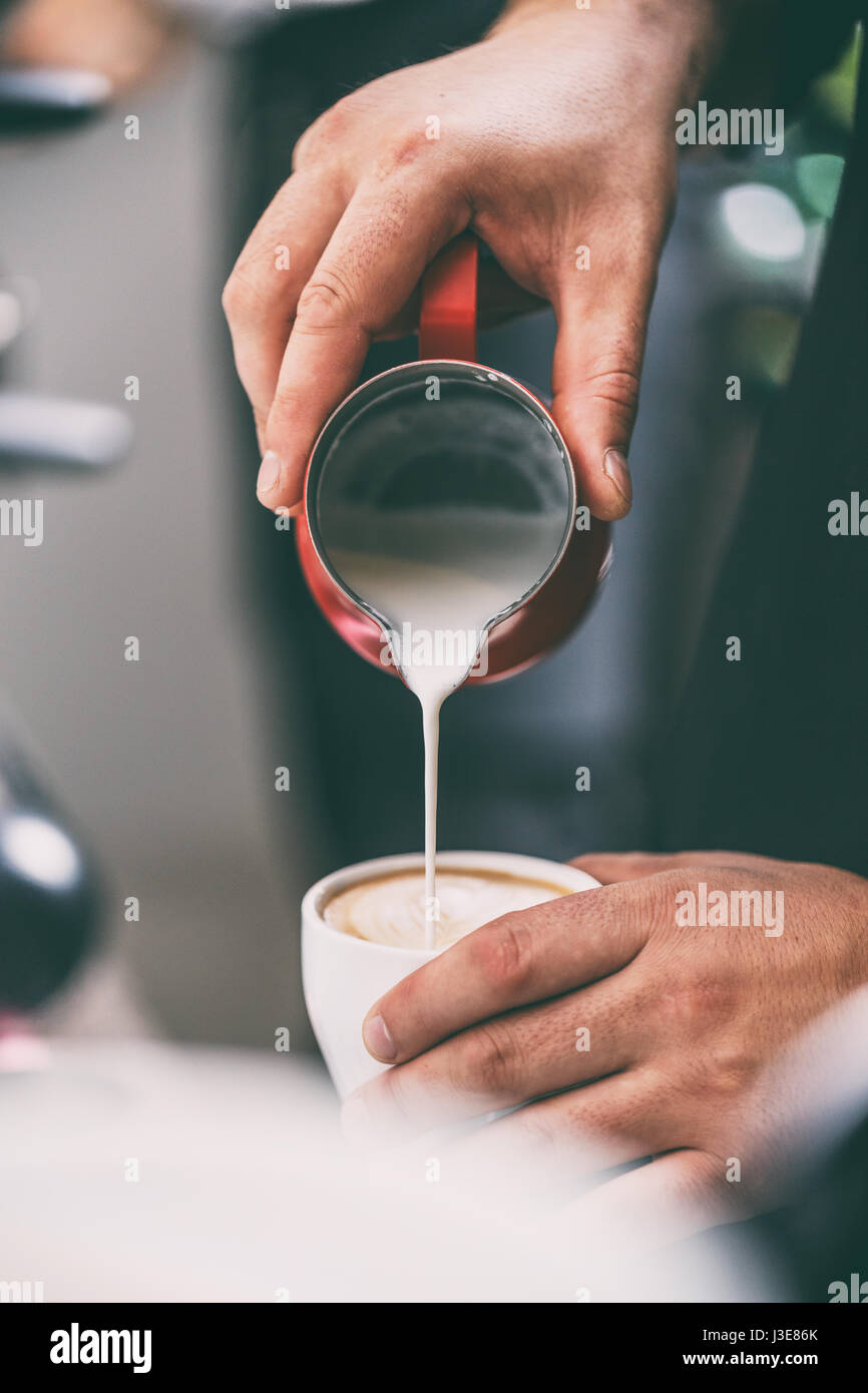 Close up of barista adding milk to coffee Stock Photo
