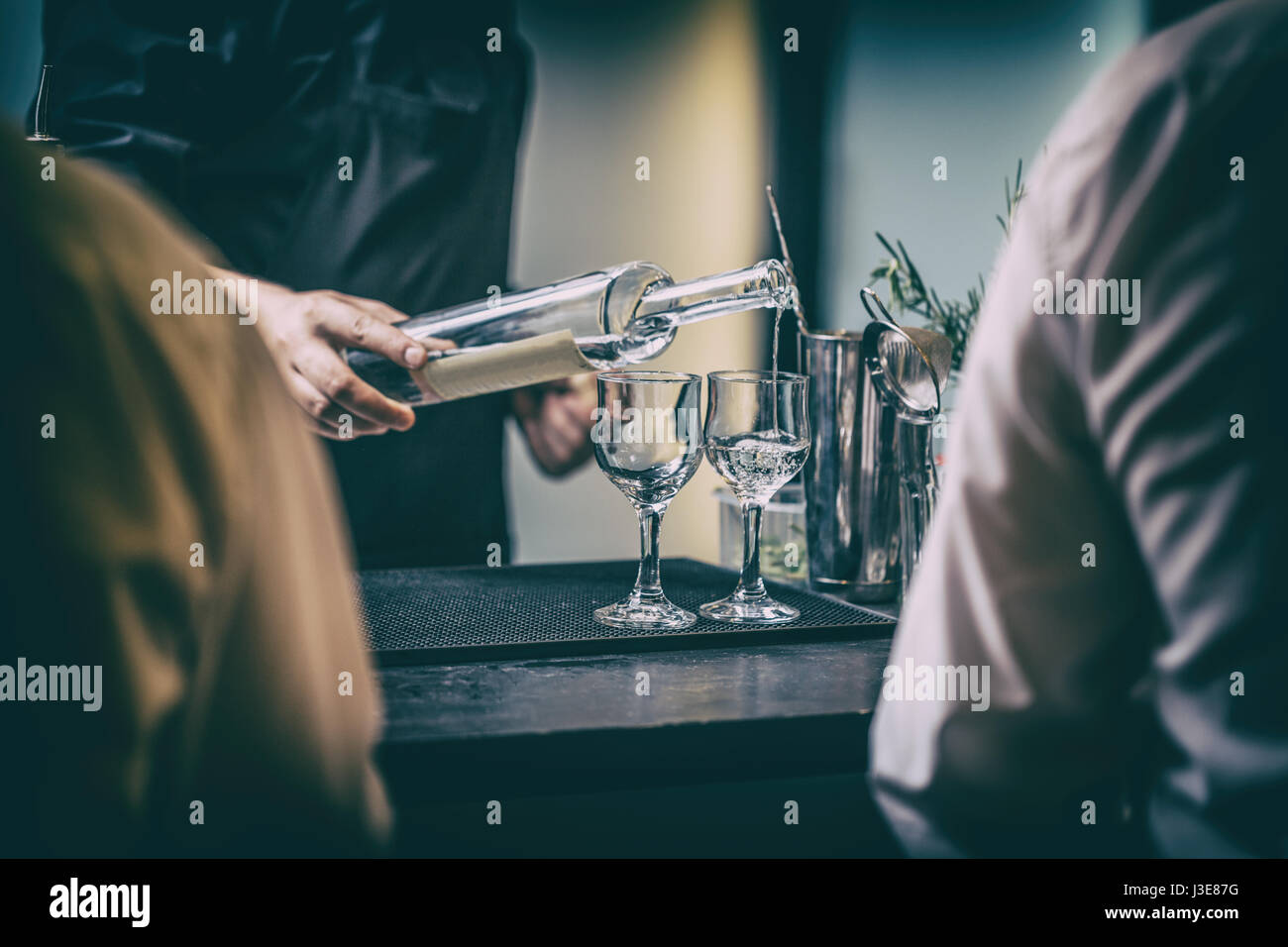 Bartender serving alcohol drinks behind bar counter. Stock Photo
