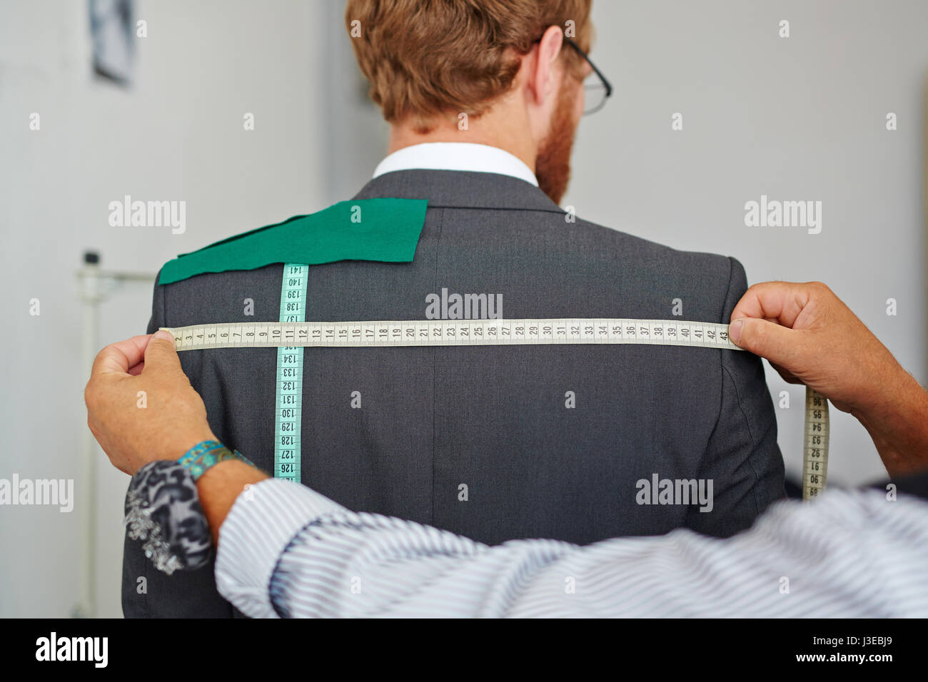 Tailor Taking Measurements on Customer Stock Photo