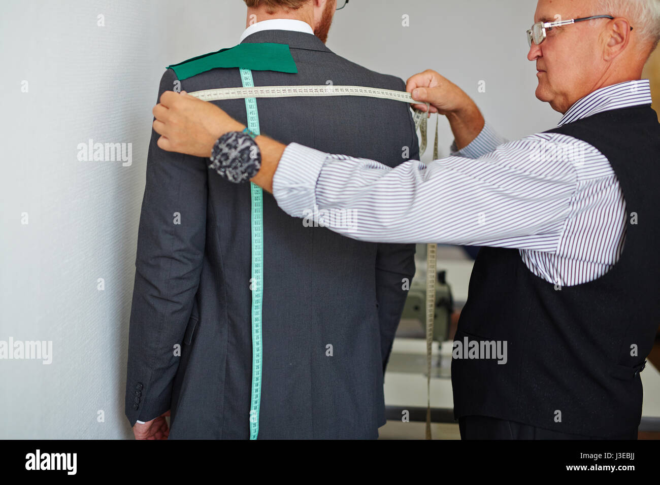 Tailor Measuring Back of Client to Make Suit Stock Photo