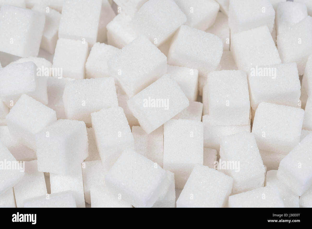 Sugar background sweet food ingredient with a close up of a pile of delicious white lumps of cubes as a symbol of cooking and baking and the diet health risks related to diabetes and calorie intake. Stock Photo