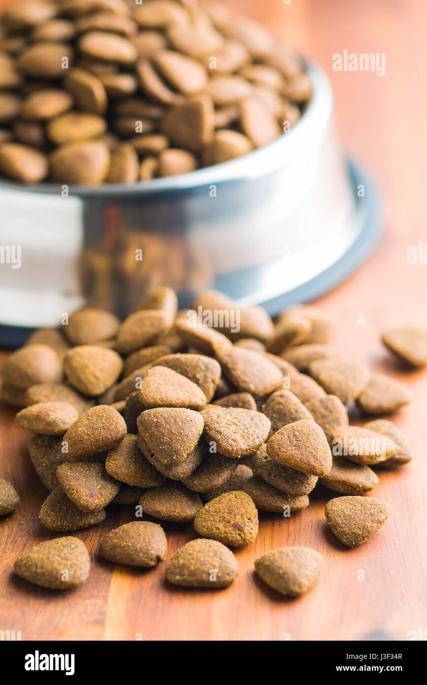 Dry kibble dog food on wooden table. Stock Photo