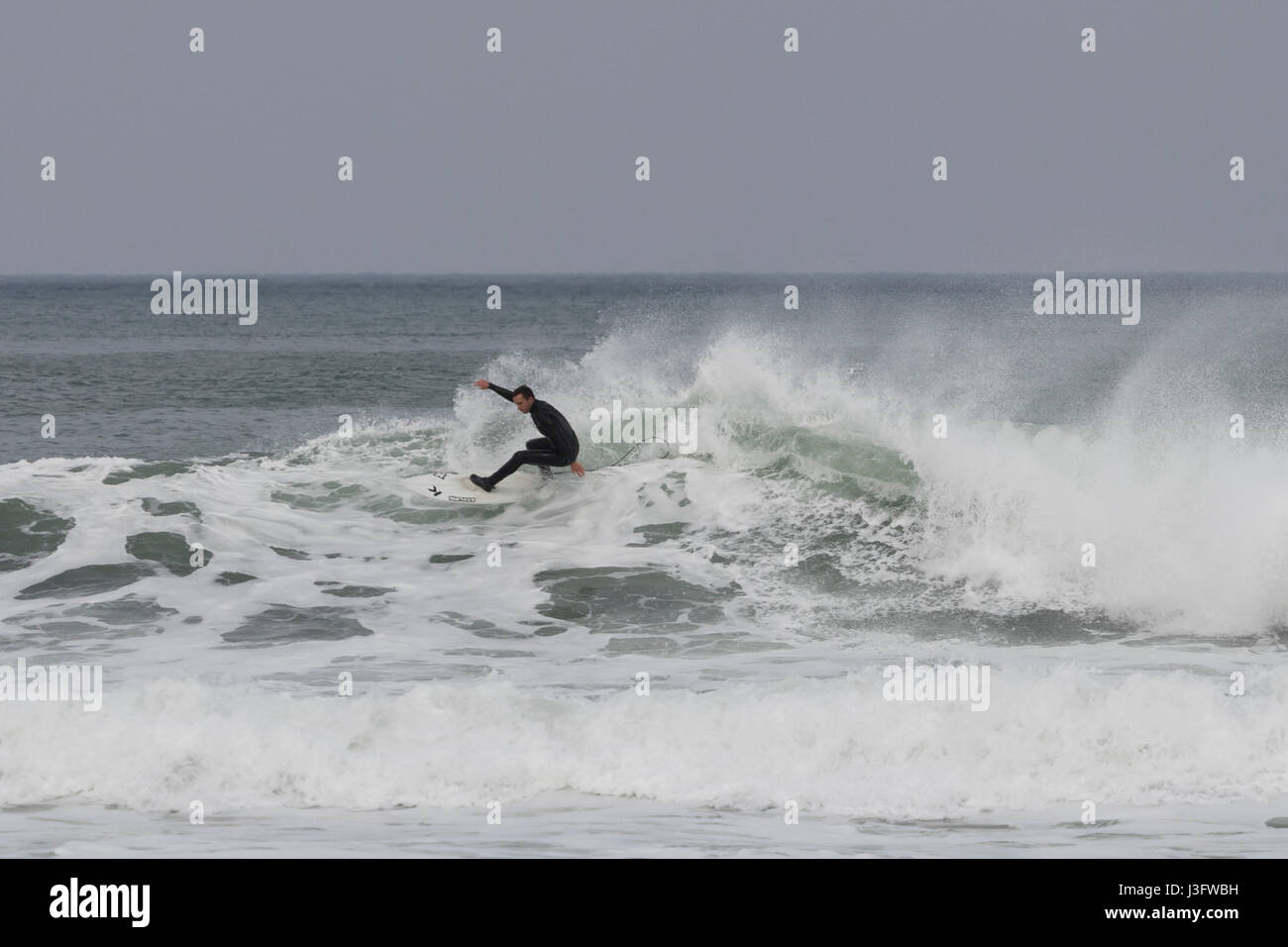 One surfer riding a wild wave full of foam in la Zurriola beach in San Sebastian (Guipuzcoa, Spain) 2017. Stock Photo