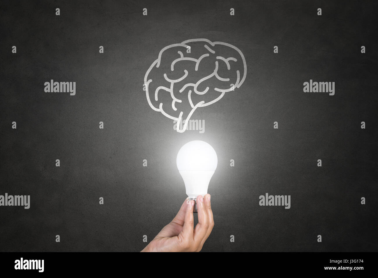 Hand holding light bulb on blackboard Stock Photo