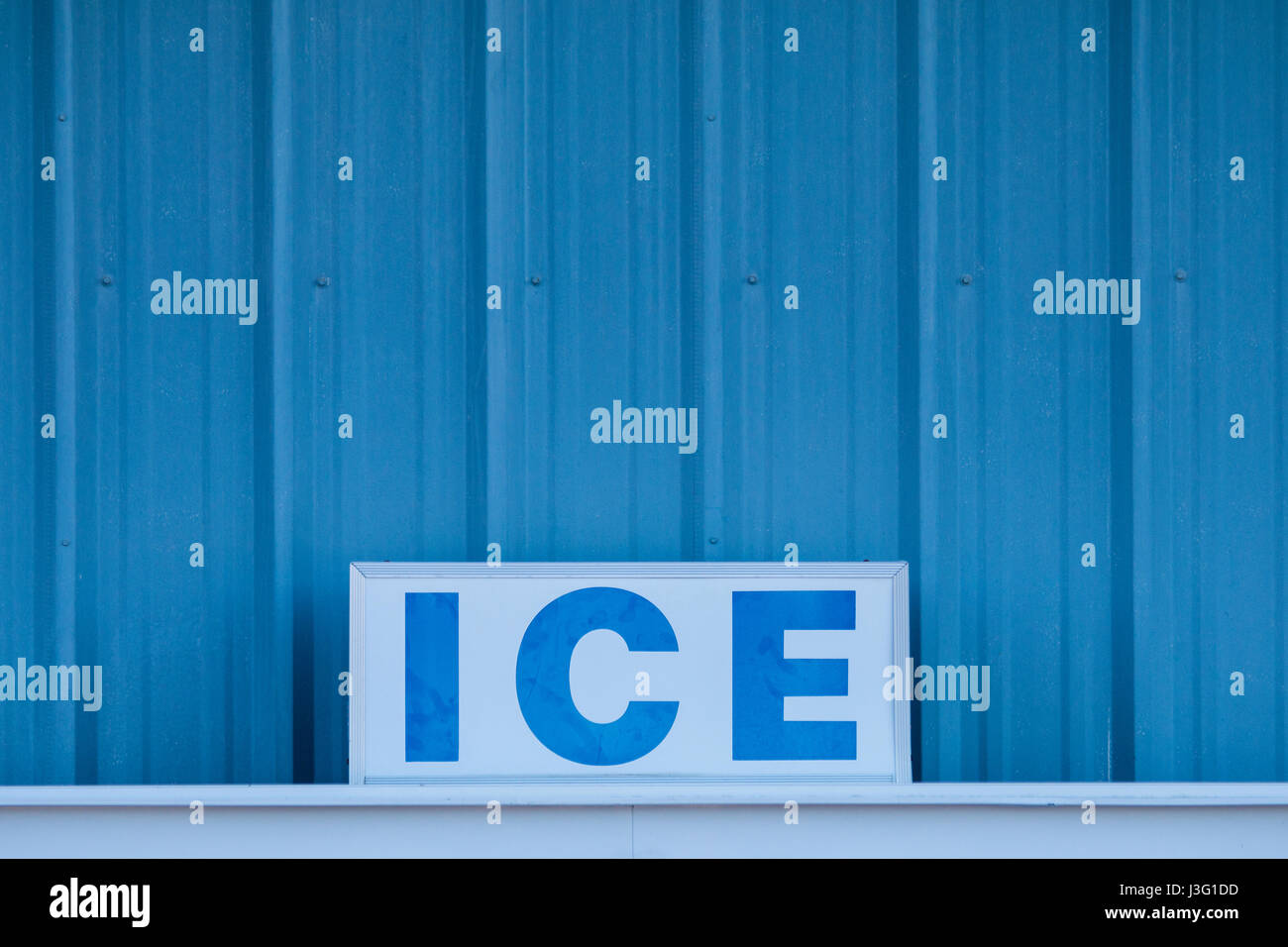 Word ICE in capital letters on sign in front of cold blue metal wall Stock Photo