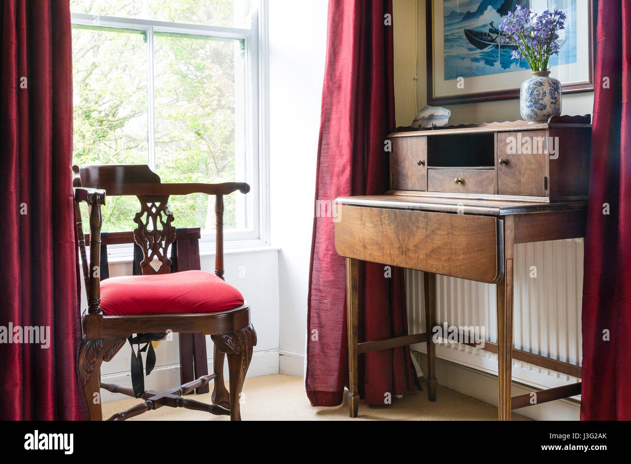 Old fashioned Georgian writing desk and chair in corner of room Stock Photo