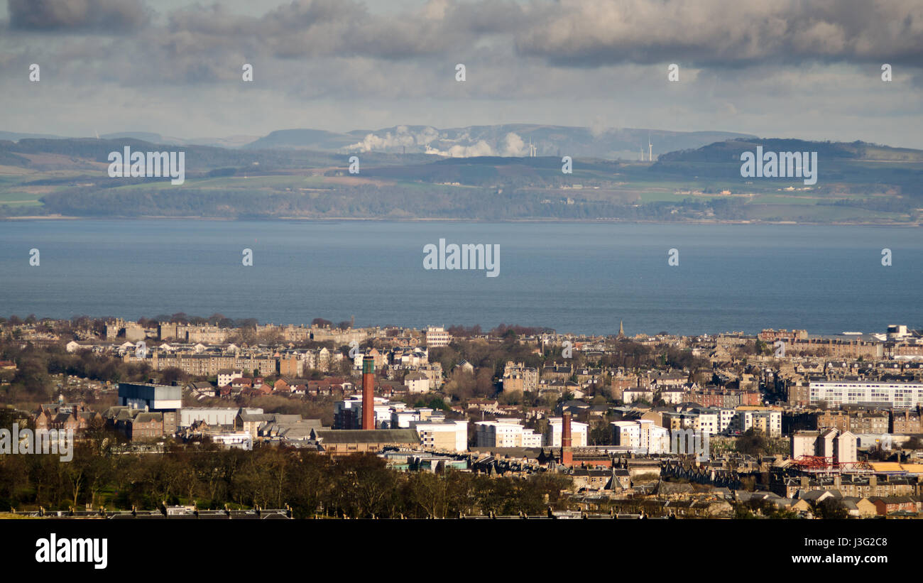 The Edinburgh suburbs lead down to the Firth of Forth, with the rolling hills of Fife rising behind, viewed from Arthur's Seat mountain. Stock Photo