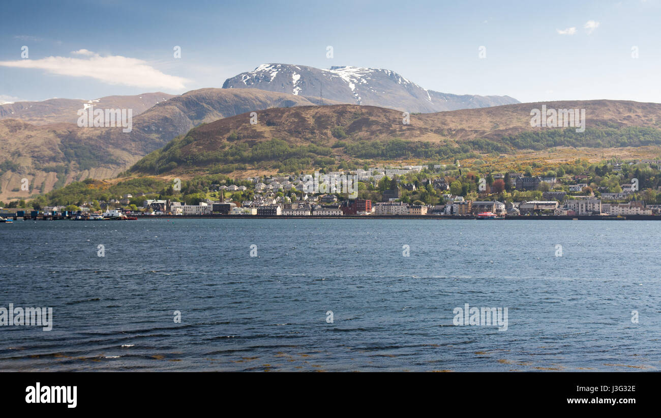 Ben Nevis, the UK's highest mountain, rises behind Loch Linnhe, with the town of Fort William on the sea shore. Stock Photo