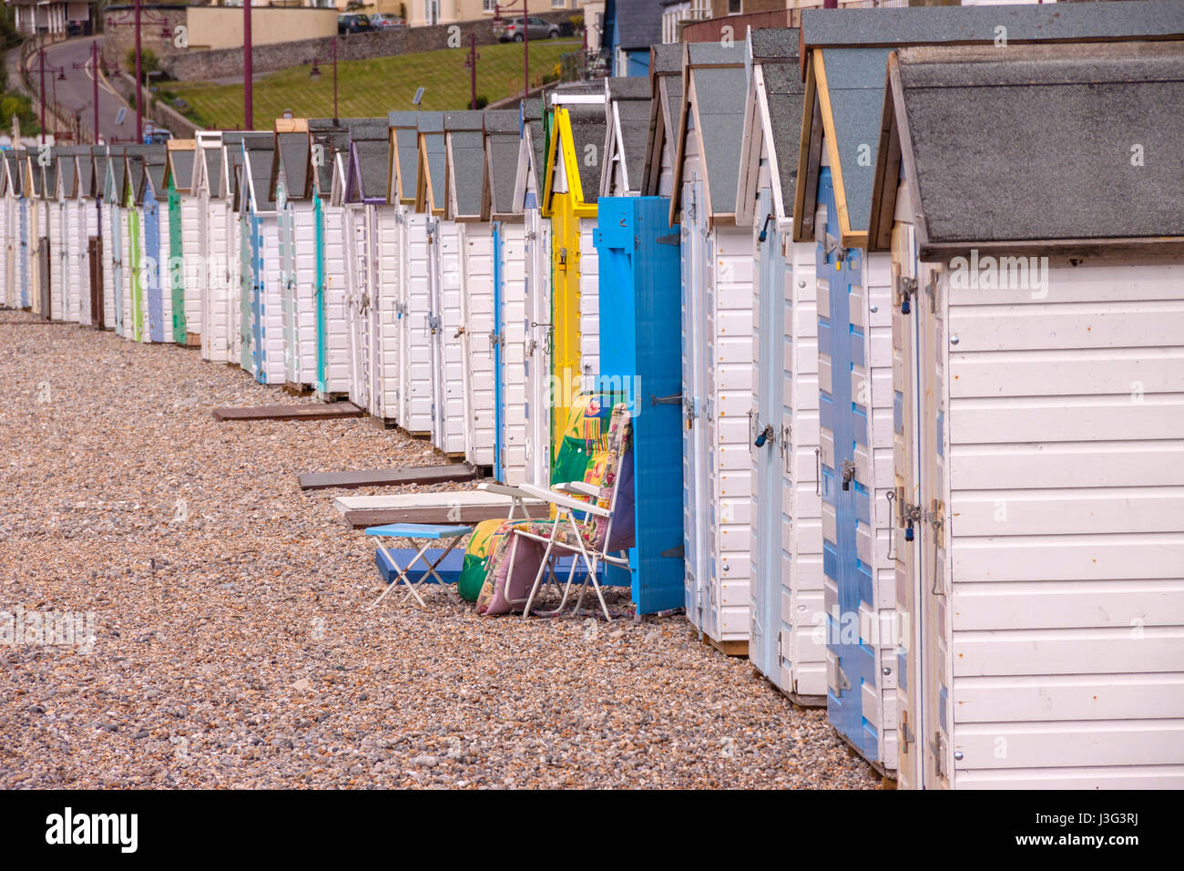 Beach huts on the beach at Seaton Devon, with blocks of flats behind. Stock Photo