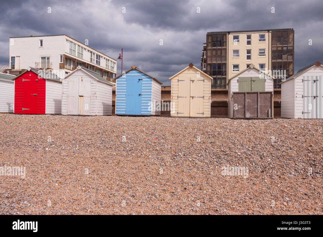 Beach huts on the beach at Seaton Devon, with blocks of flats behind