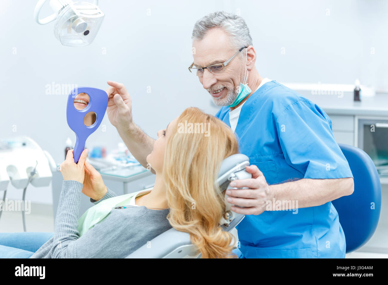 senior dentist in uniform talking with patient in dental clinic Stock