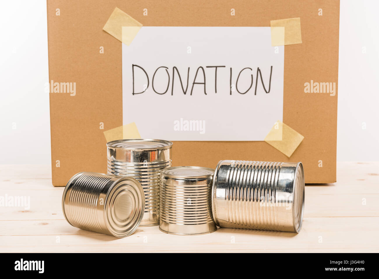 tin cans with cardboard donation sign donation on wooden table on white