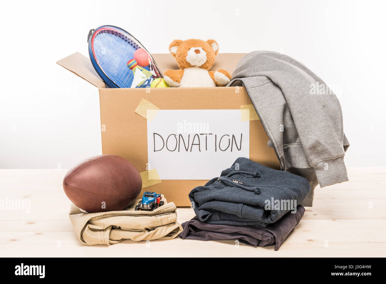 cardboard box with donation clothes and different objects on white, donation concept Stock Photo